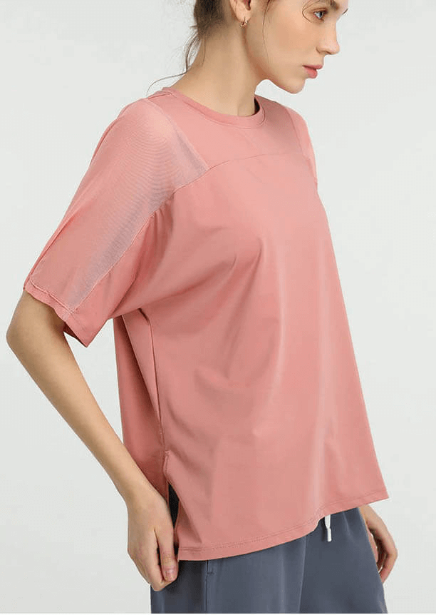 Woman wearing a loose pink mesh short sleeve t-shirt, ideal for women's sports and workout activities, showcasing comfort and style.